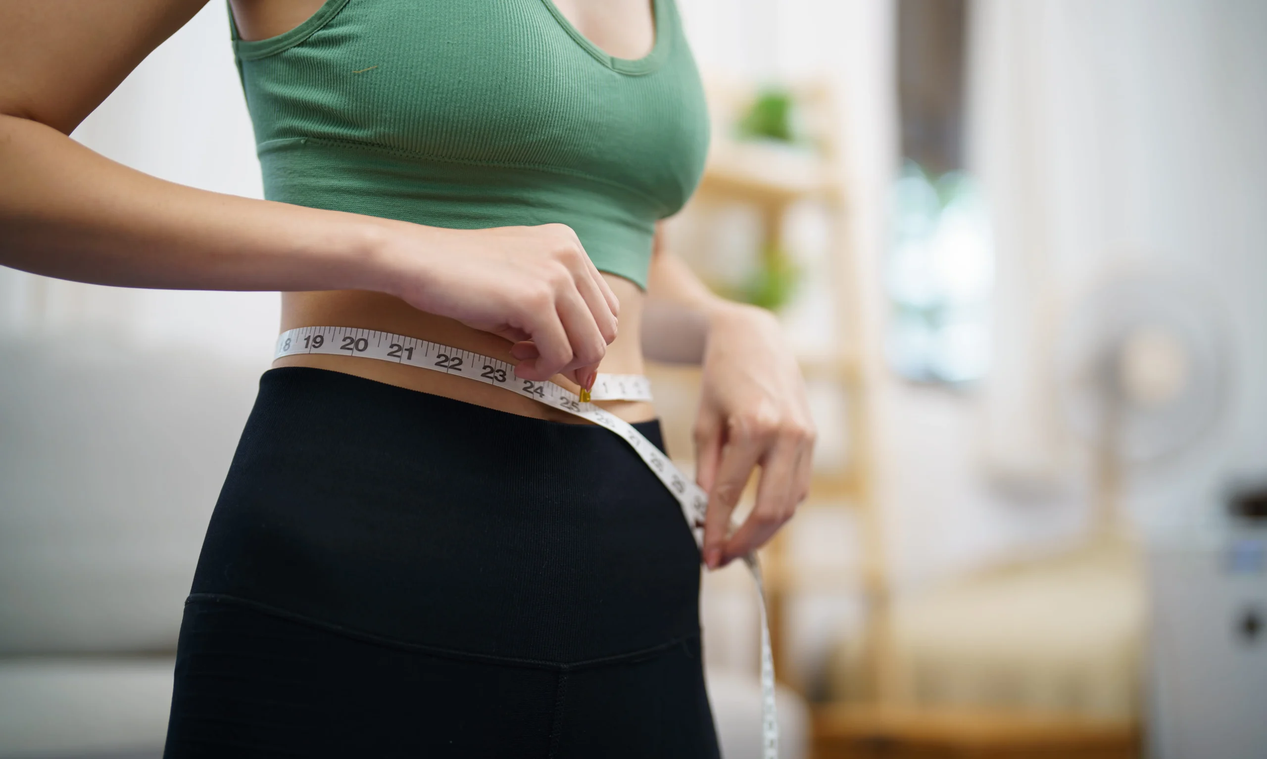 Woman measuring her waist during a personalized metabolic health and weight loss program in Peoria, AZ